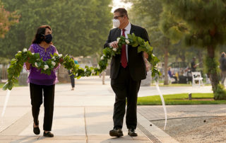 Fresno State President Joseph I. Castro and labor leader and civil rights activist Dolores Huerta carry a flower garland in the Peace Garden at Fresno State.