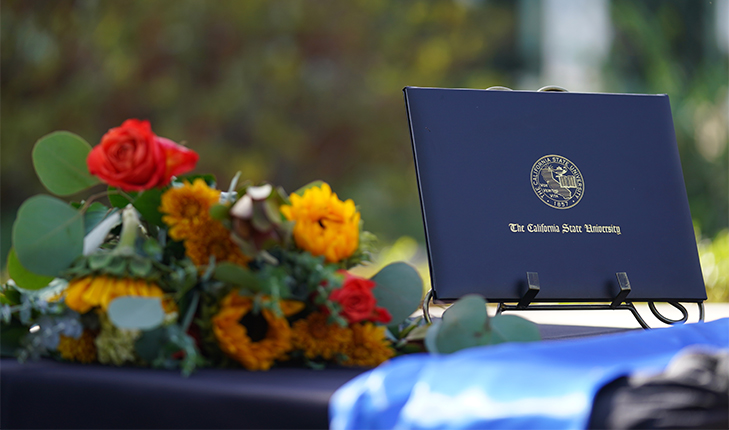 A Fresno State degree sits on a table next to an assortment of flowers