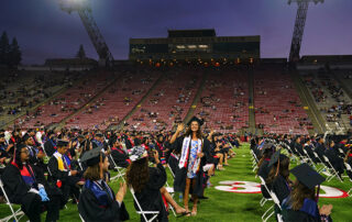 Student stands during Fresno State's 2020-21 graduation ceremony at Bulldog Stadium.