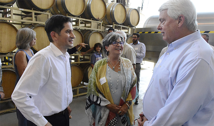 President Saul Jimenez-Sandoval and other individuals speaking with wine barrels in the background