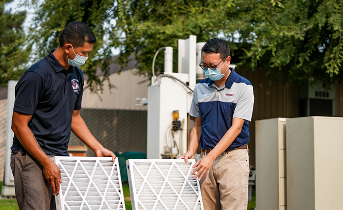 Vincent Malpaya, left, and Dr. Deify Law look at air filters used in an indoor air quality research project.