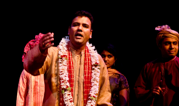 A young man performing on stage, motioning to the audience.