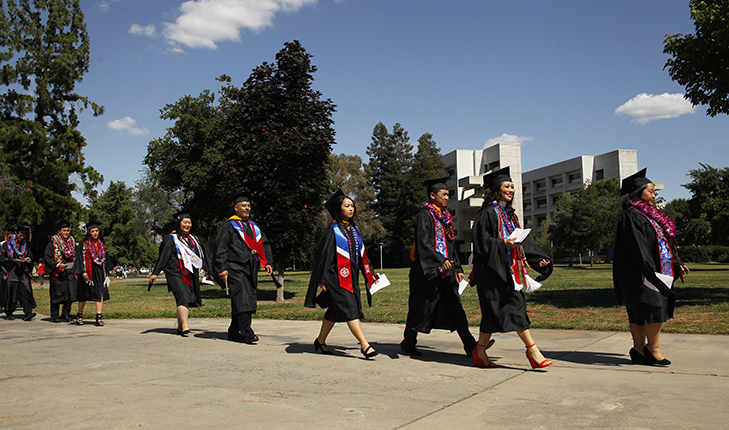 Hmong and Asian-Americans walking with their graduation gowns and caps.