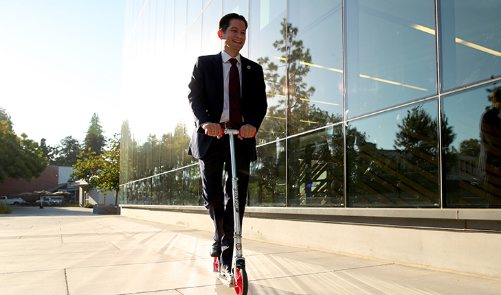 Provost Jiménez-Sandoval riding a scooter to get to his meeting.