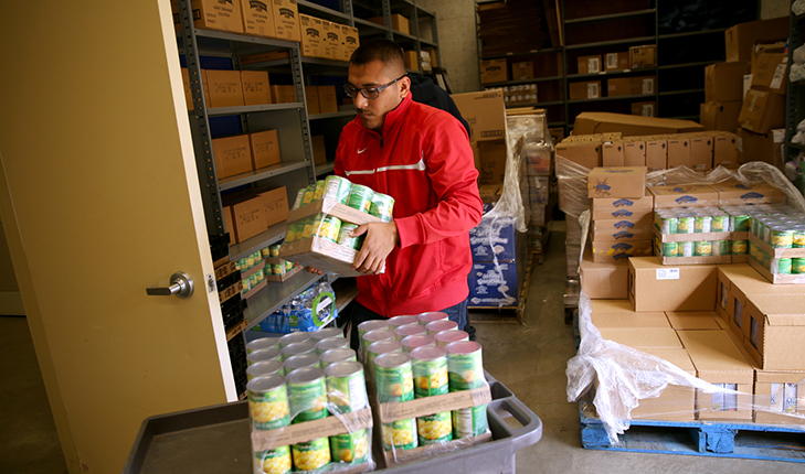 Young man stocks shelves at the Fresno State Student Cupboard.