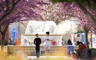 Two students walk in front of the fountain at Fresno State.