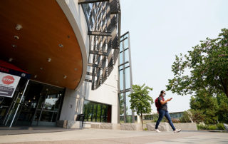 Student walking in front of the Henry Madden Library.