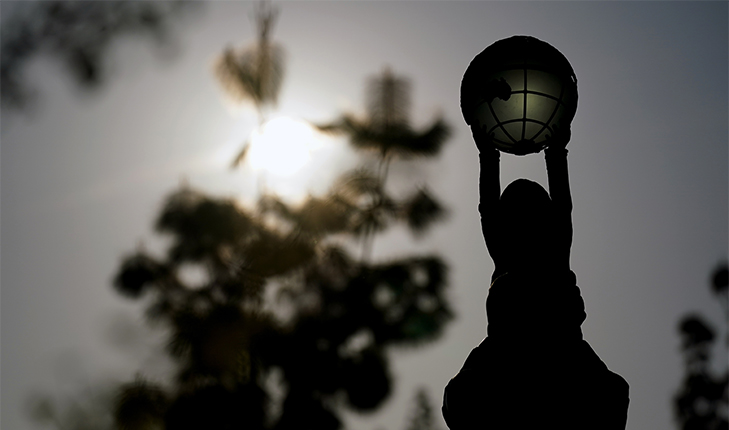 A view of the sun from behind the Jan Adams statue on campus.