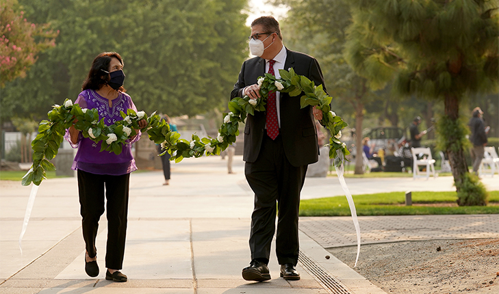 Fresno State President Joseph I. Castro and labor leader and civil rights activist Dolores Huerta carry a flower garland in the Peace Garden at Fresno State.