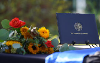 A Fresno State degree sits on a table next to an assortment of flowers
