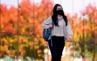 Student walks on campus wearing face mask during COVID-19 pandemic.