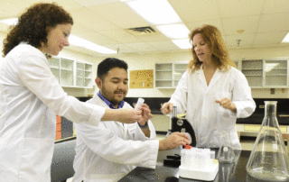 Graduate student Jonas Gomez works with professors in the lab.