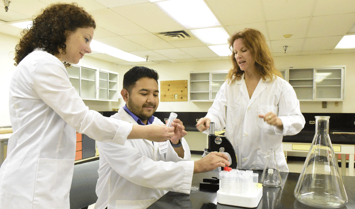 Graduate student Jonas Gomez works with professors in the lab.
