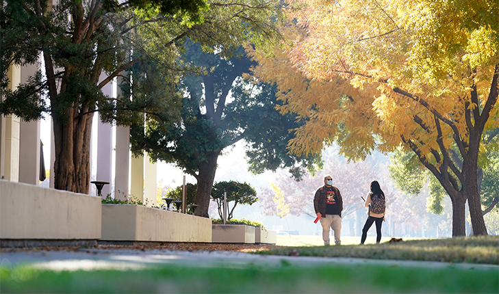 Masked students talk on campus