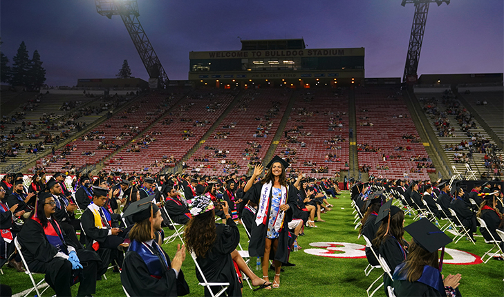 Student stands during Fresno State's 2020-21 graduation ceremony at Bulldog Stadium.