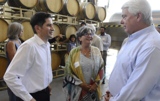 President Saul Jimenez-Sandoval and other individuals speaking with wine barrels in the background