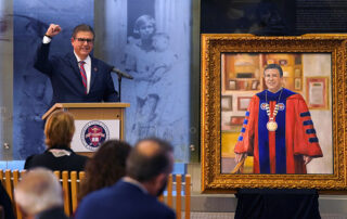 CSU Chancellor Joseph I. Castro raises his fist in a triumphant gesture at the unveiling of his presidential portrait.
