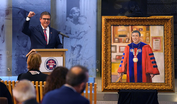 CSU Chancellor Joseph I. Castro raises his fist in a triumphant gesture at the unveiling of his presidential portrait.