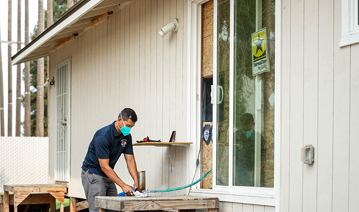 Vincent Malpaya starts a fire out of wood chips and sends smoke through a tube into a small building.