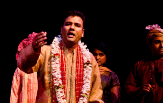 A young man performing on stage, motioning to the audience.
