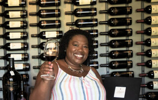 Dr. Monique Bell smiling and holding a glass of wine.