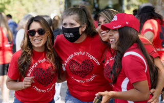 Four young women in red t-shirts smile as their photo is being taken