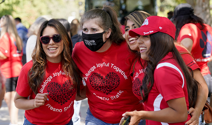 Four young women in red t-shirts smile as their photo is being taken