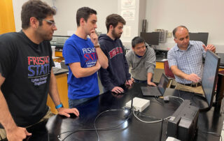 Engineering students meet with their professor.