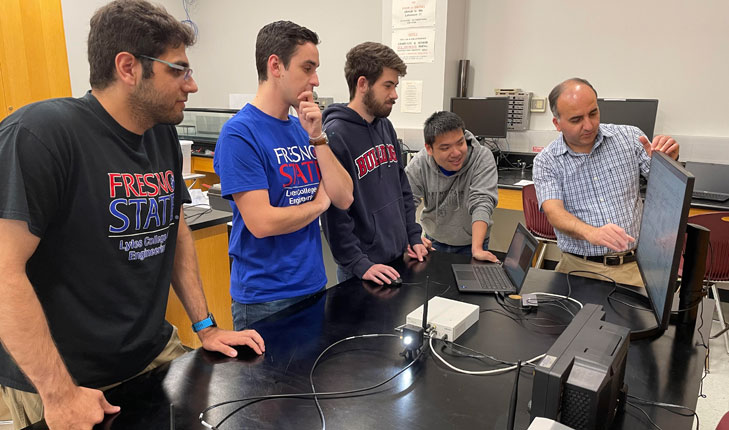 Engineering students meet with their professor.