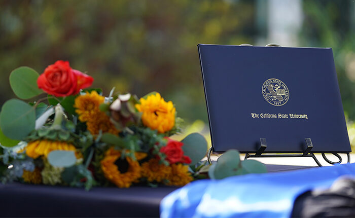 Degree folder next to a bunch of flowers.