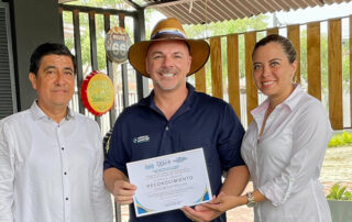 Dr. Bryan Tune posing with a recognition award in the middle of two other people.