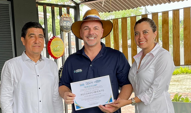 Dr. Bryan Tune posing with a recognition award in the middle of two other people.