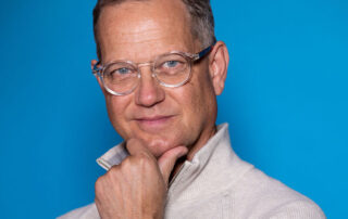 Benjamin Boone posing for a picture with a blue background.