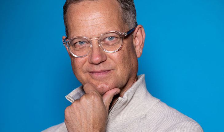 Benjamin Boone posing for a picture with a blue background.