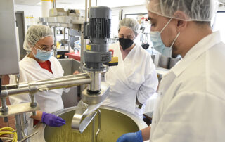 3 students standing around a mixing bowl in the Creamery.