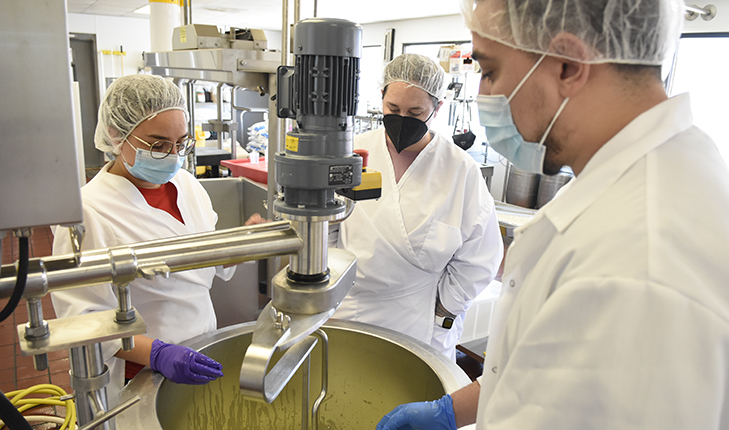 3 students standing around a mixing bowl in the Creamery.