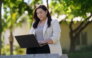 Samantha Patricia Navarro with laptop and trees behind her.