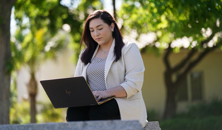 Samantha Patricia Navarro with laptop and trees behind her.