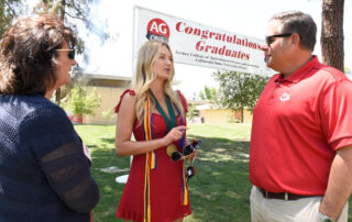 Kjar in red shirt speaking with student.