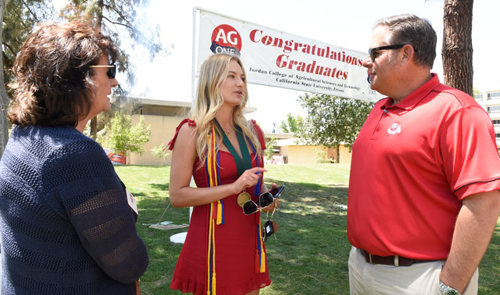 Kjar in red shirt speaking with student.