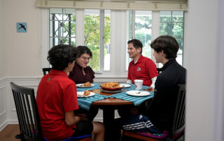 Fresno State President ​Saúl Jiménez-Sandoval, his wife Mariana Anagnostopoulos and their two sons, Arion and Leo sitting at their dining table.