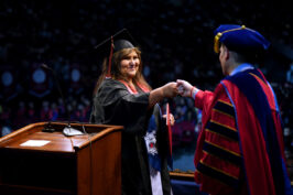 Shirley Jones fist-bumps Fresno State President Saul Jimenez-Sandoval, whose speech at Fowler High School's graduation inspired her to keep going in pursuit of her degree.