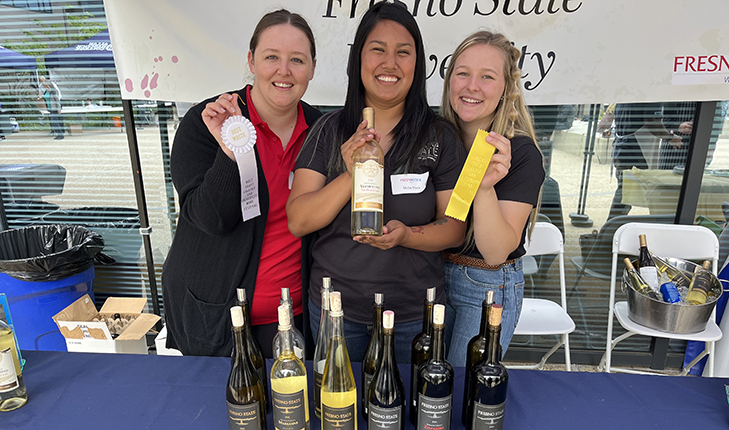 Students holding up wine and awards