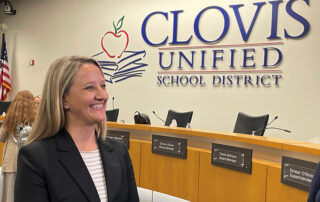 Dr. Corrine Folmer in front of "Clovis Unified School District" sign