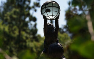 Statue of child holding up globe.