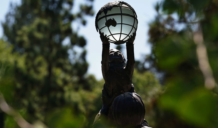 Statue of child holding up globe.