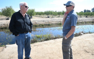 Fresno State retired engineering faculty Cordie Qualle discusses a aquifer groundwater recharge project he helped design at the location site next to a campus almond orchard with Bill Green, education specialist for the Fresno State Center for Irrigation Technology, photo by Geoff Thurner