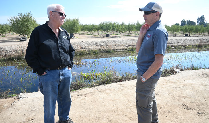 Fresno State retired engineering faculty Cordie Qualle discusses a aquifer groundwater recharge project he helped design at the location site next to a campus almond orchard with Bill Green, education specialist for the Fresno State Center for Irrigation Technology, photo by Geoff Thurner