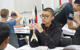 Student makes a rocket at an engineering summer camp for school children.