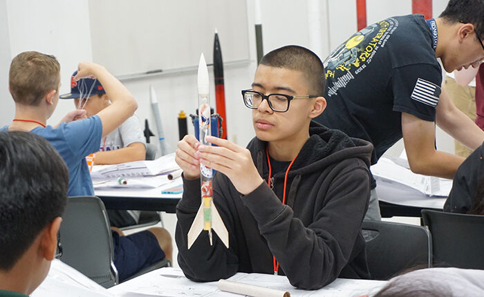 Student makes a rocket at an engineering summer camp for school children.